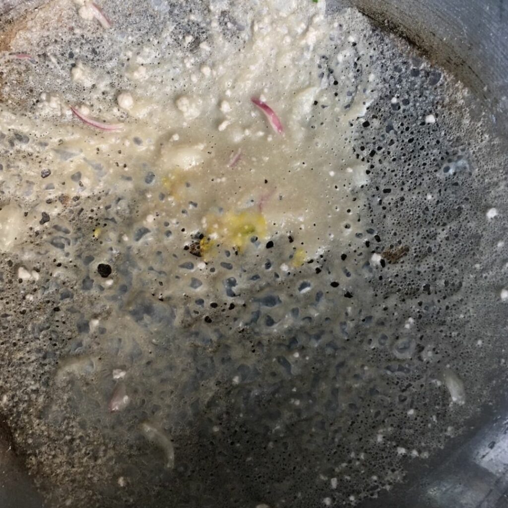 การทำขนมกรอก ละเลงแป้งที่เตรียมไว้เป็นแผ่นบาง ๆ ให้ทั่วกะทะ 